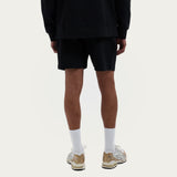 Model draagt de Branded Sweater en Branded Shorts in zwart, achteraanzicht