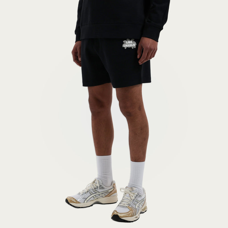 Model draagt de Branded Sweater en Branded Shorts in zwart, vooraanzicht